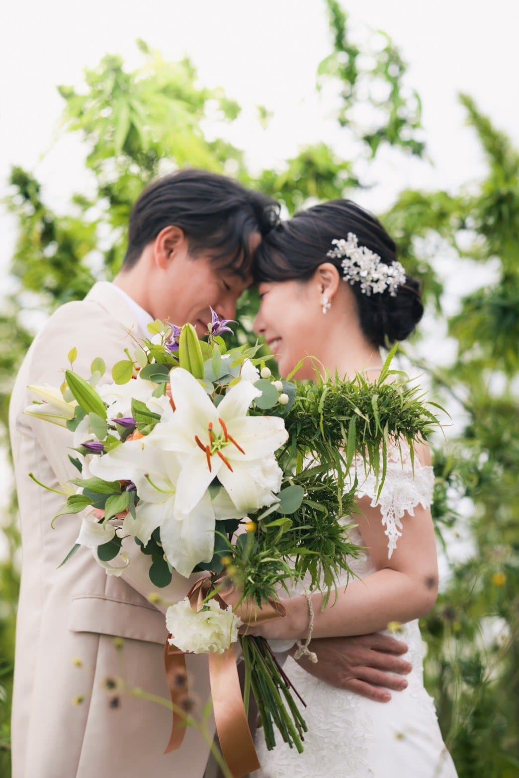 麻畑で額を寄せ合う新郎新婦。花嫁は麻の葉をあしらったブーケを持っている